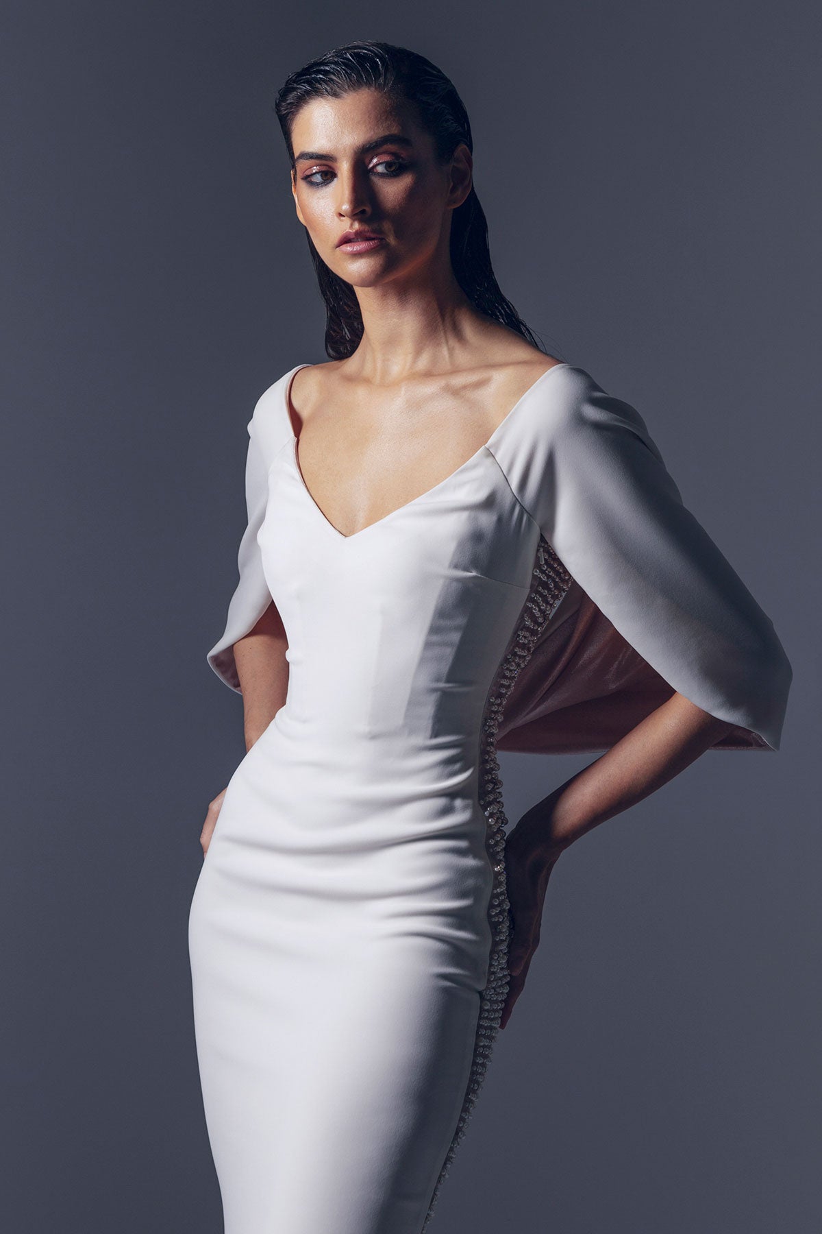 Off-shoulder white crepe dress with a fitted bodice.